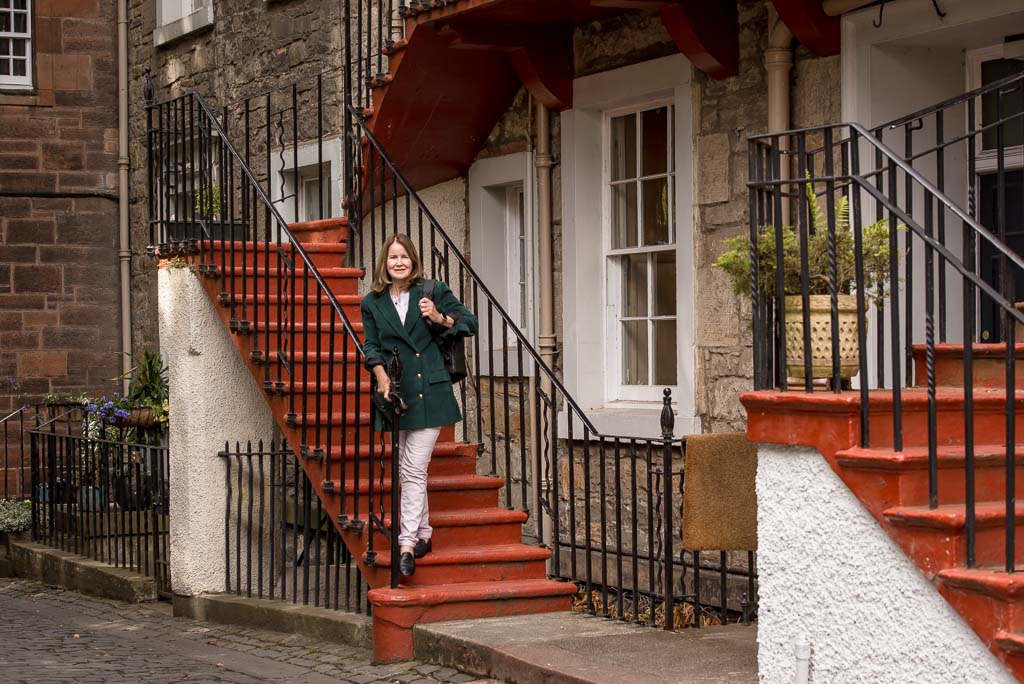 Seasonal brand photography in Edinburgh, Scotland, showing woman in dark green jacket on steps just off the Royal Mile