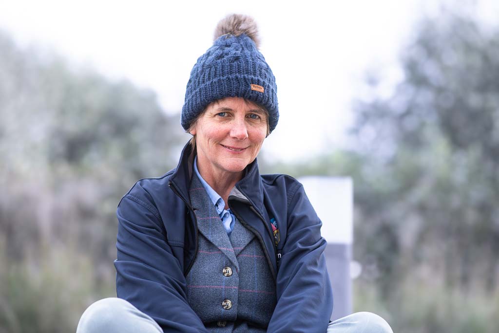 Brand photographer Edinburgh Scotland | woman wearing blue Harris tweed waistcoat and blue Barbour bobble hat